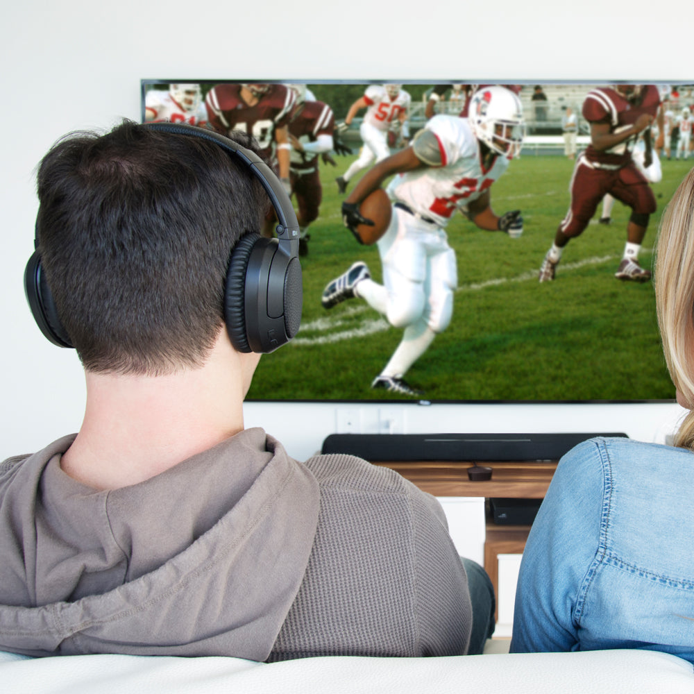 Two people watching a football game on TV with MEE audio Matrix Cinema Bluetooth Wireless headphones.