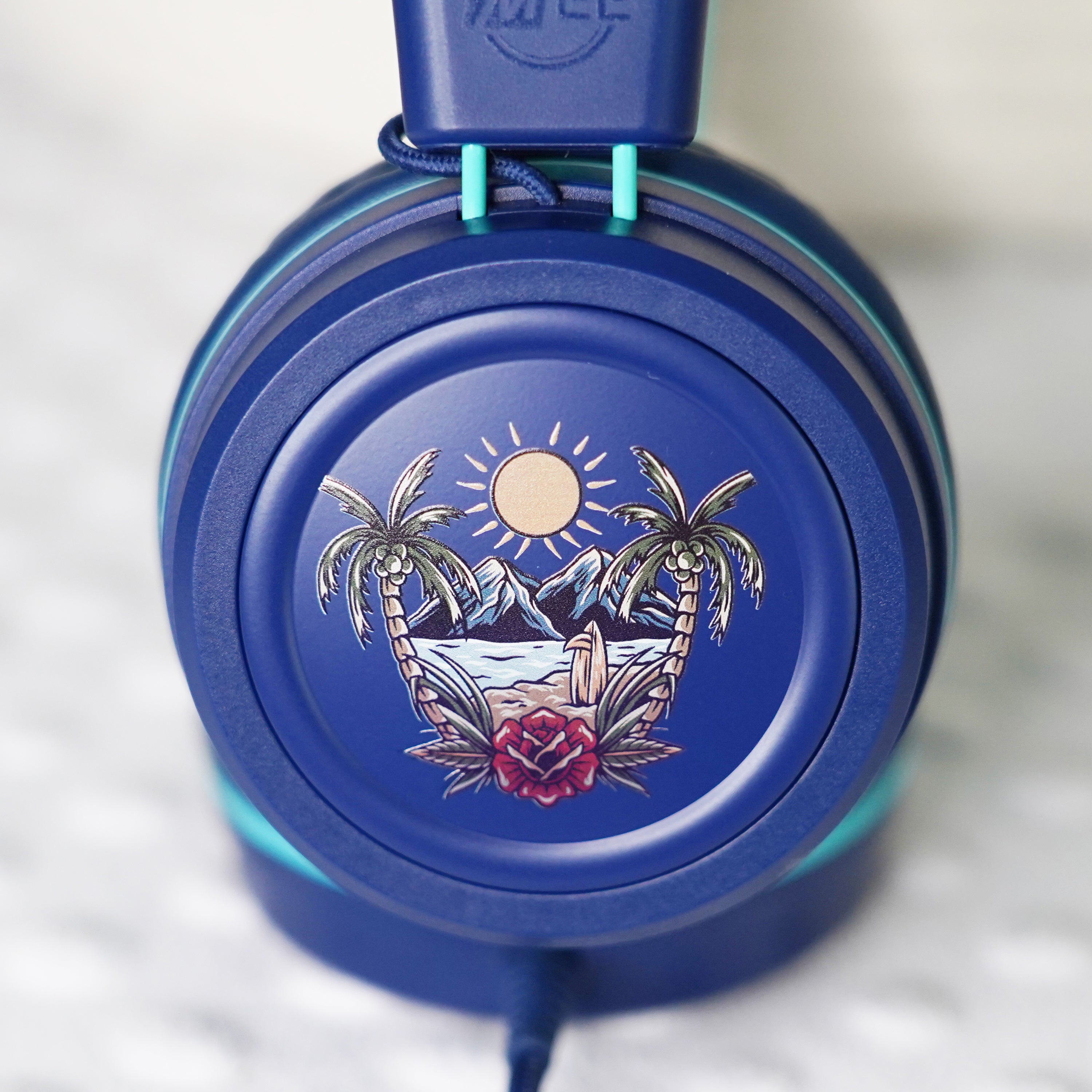 Blue KidJamz KJ55AUX headphones faceplate with a tropical design in color on a light gray background