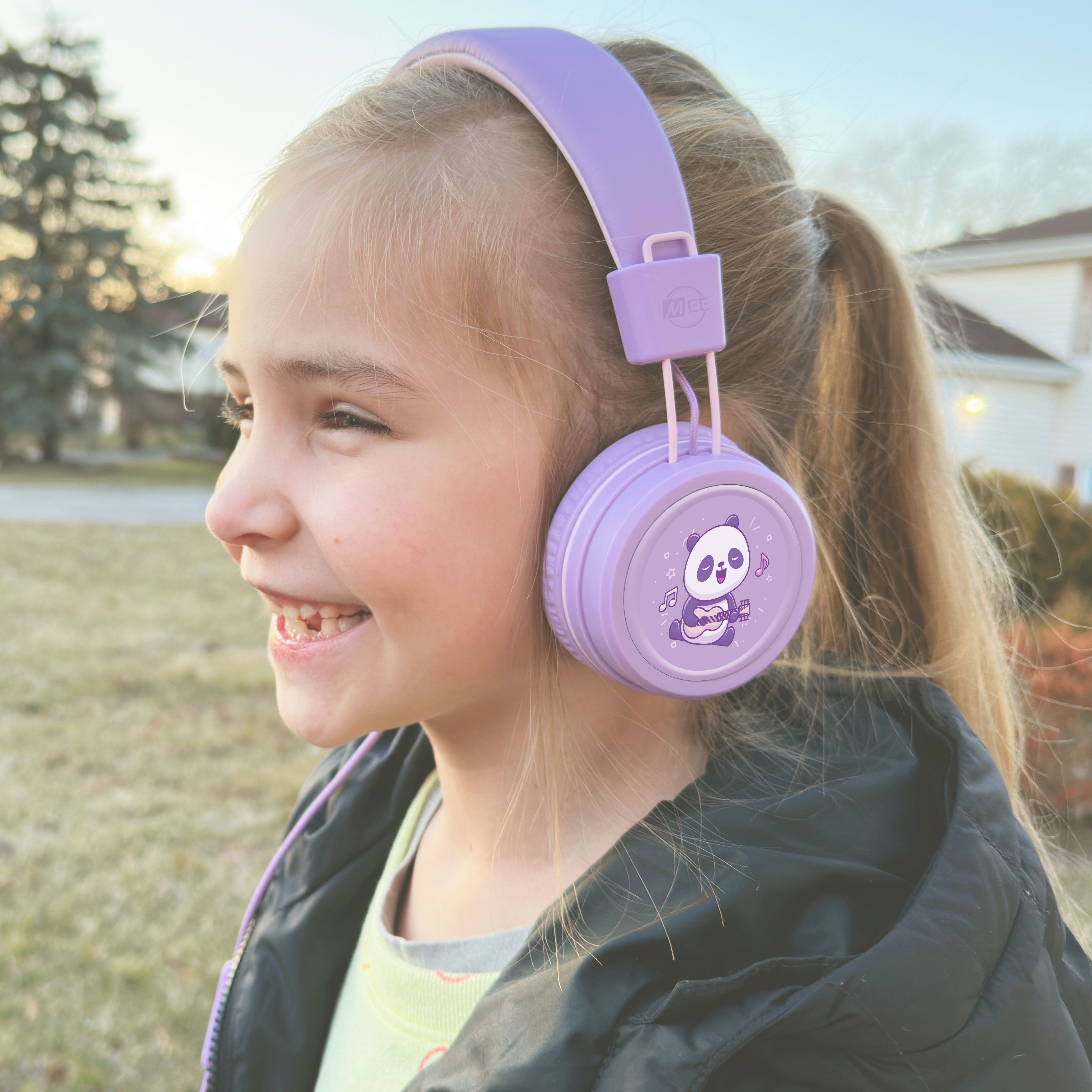Young girl wearing Lavender KidJamz KJ55AUX headphones with a panda design in color while outdoors.