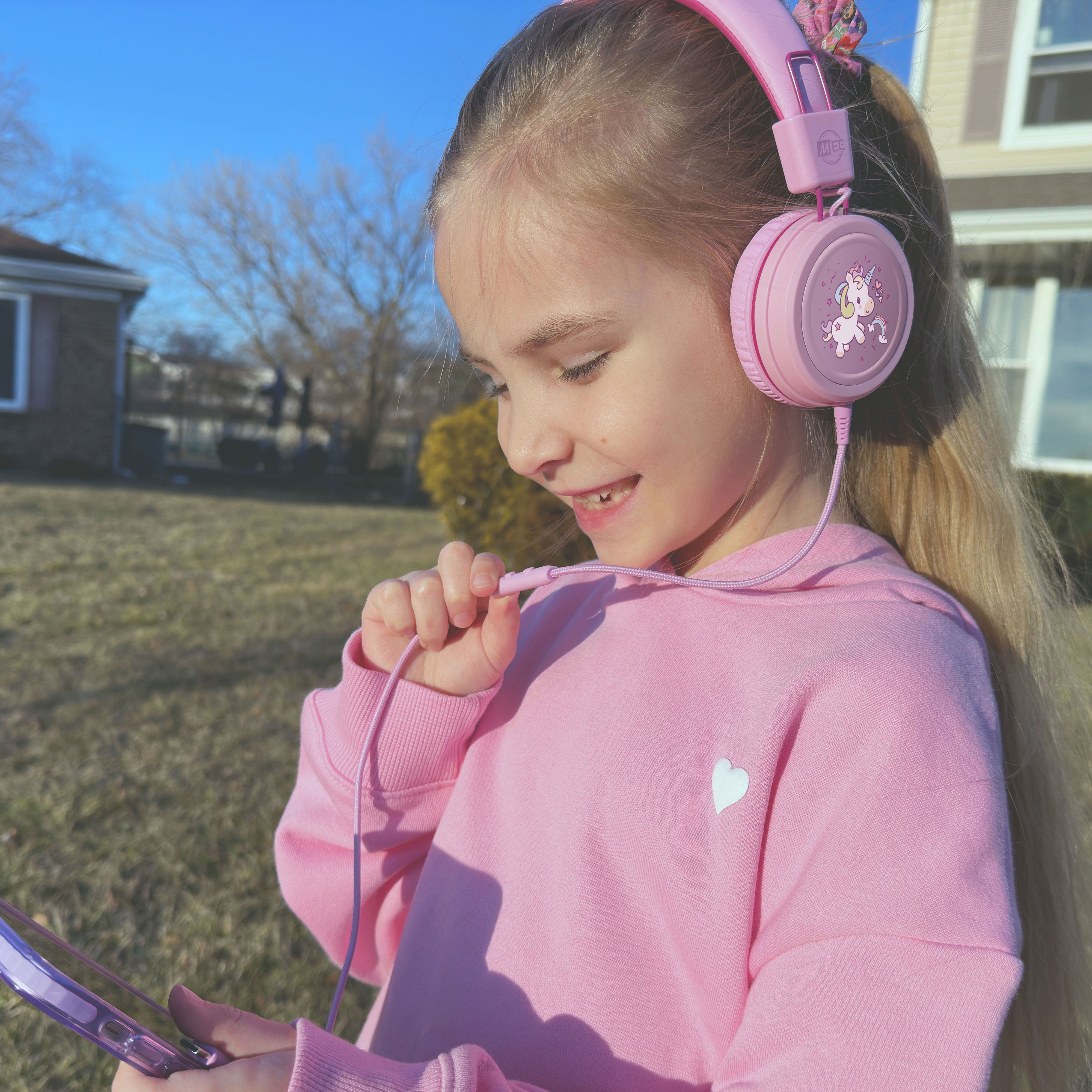 Child wearing MEE audio KidJamz KJ55 Wired Children’s Headphones with 3.5mm Plug, Colorful Graphics, Volume Limiter & Microphone, Adjustable On-Ear Kids Headset for Online Learning/School/Travel/Tablet