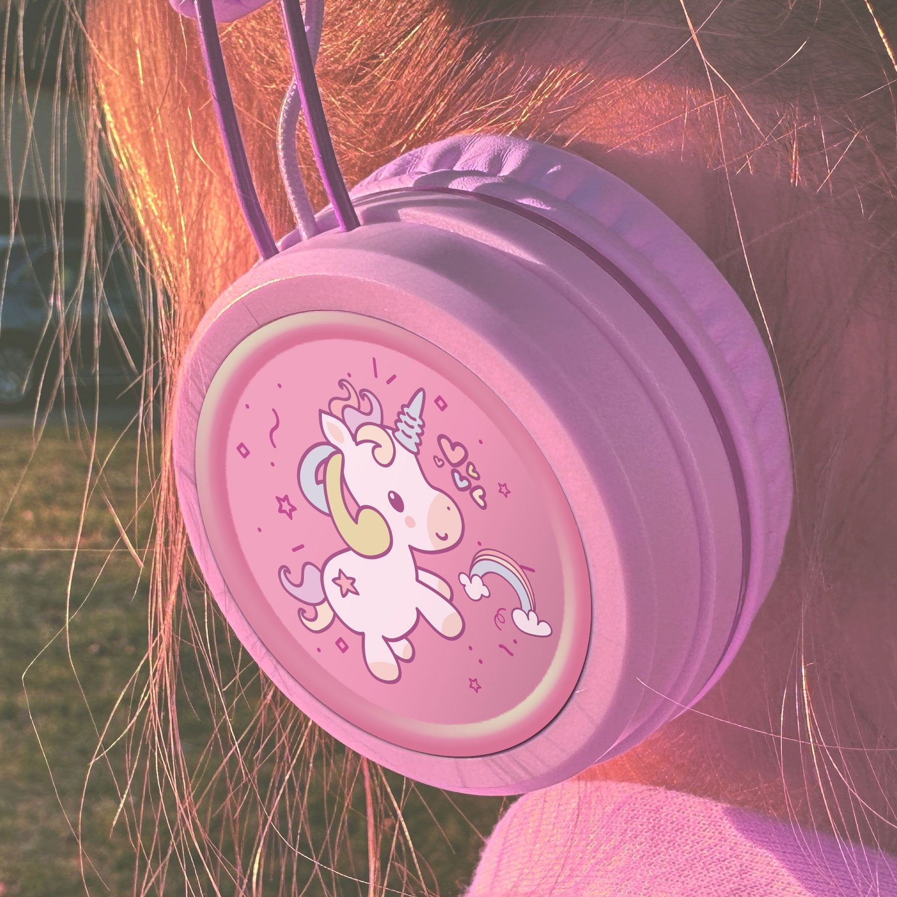 Pink KJ55AUX headphones with a unicorn design on a child's head.