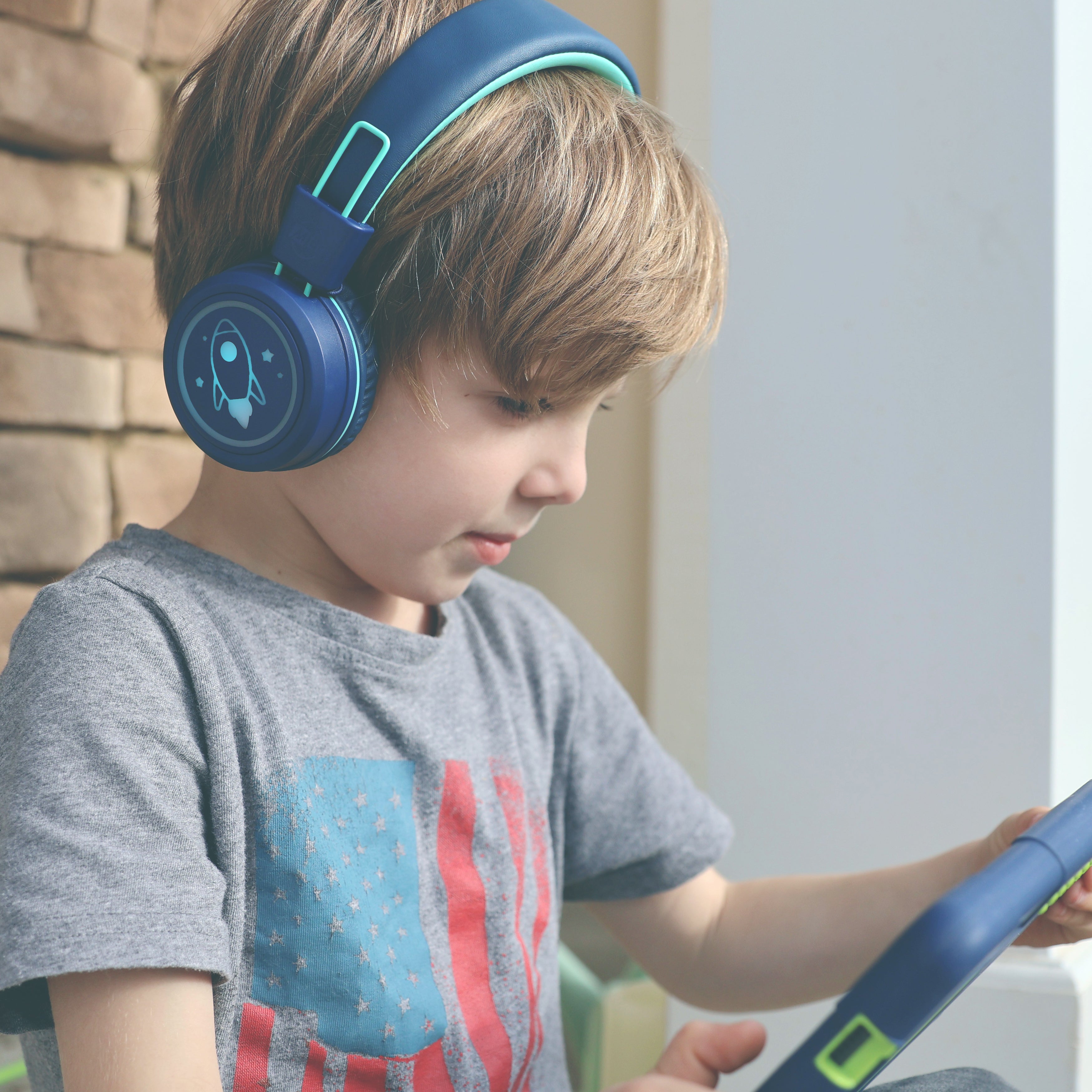 Image of a boy wearing MEE audio KidJamz KJ55BT Bluetooth Wireless Safe Listening Headphones for Children with LED Lights, 85dB Volume Limiter, Microphone, & 40h battery; Kids Headset for School / iPhone / iPad / Tablet