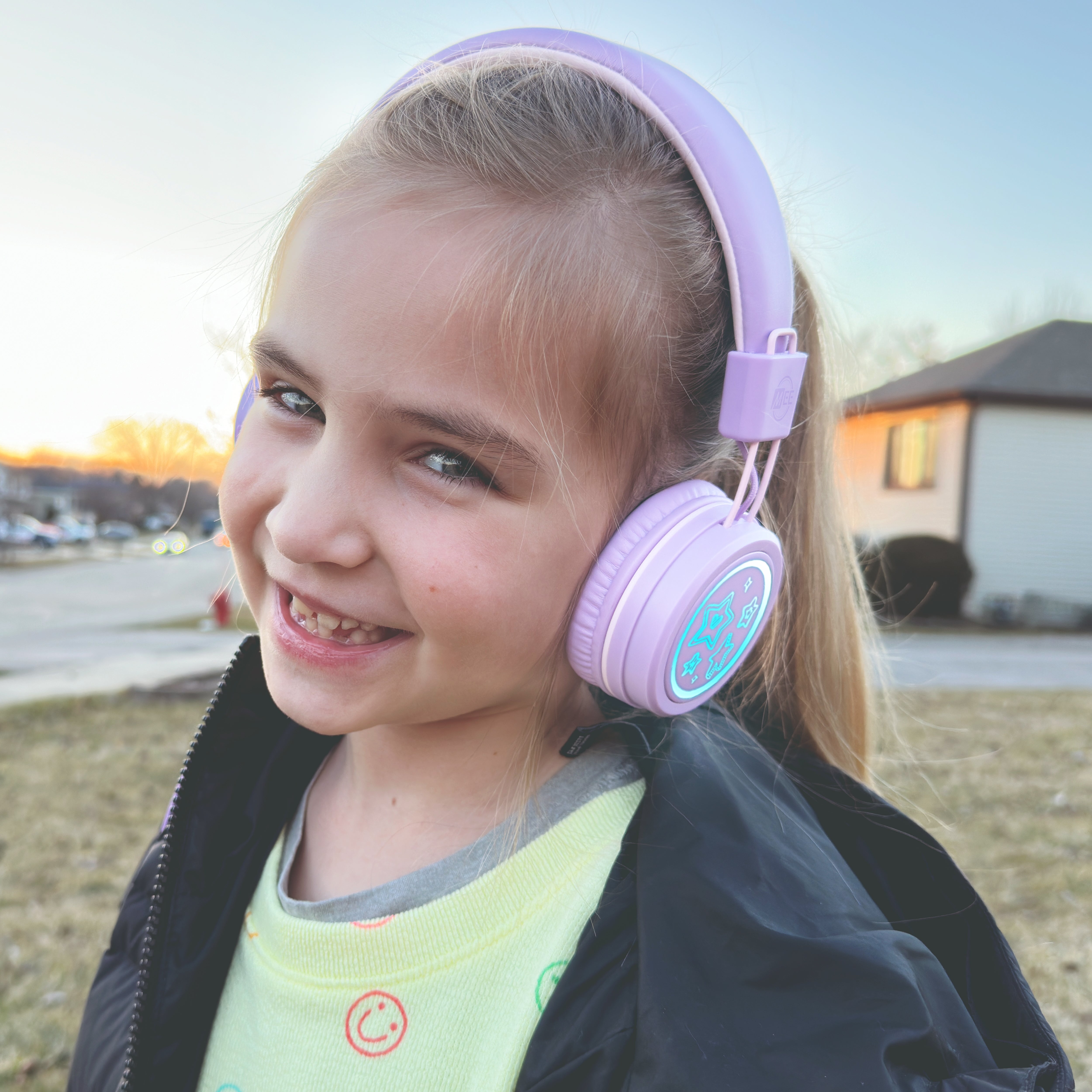 Image of a girl wearing the MEE audio KidJamz KJ55BT Bluetooth Wireless Safe Listening Headphones for Children with LED Lights, 85dB Volume Limiter, Microphone, & 40h battery; Kids Headset for School / iPhone / iPad / Tablet