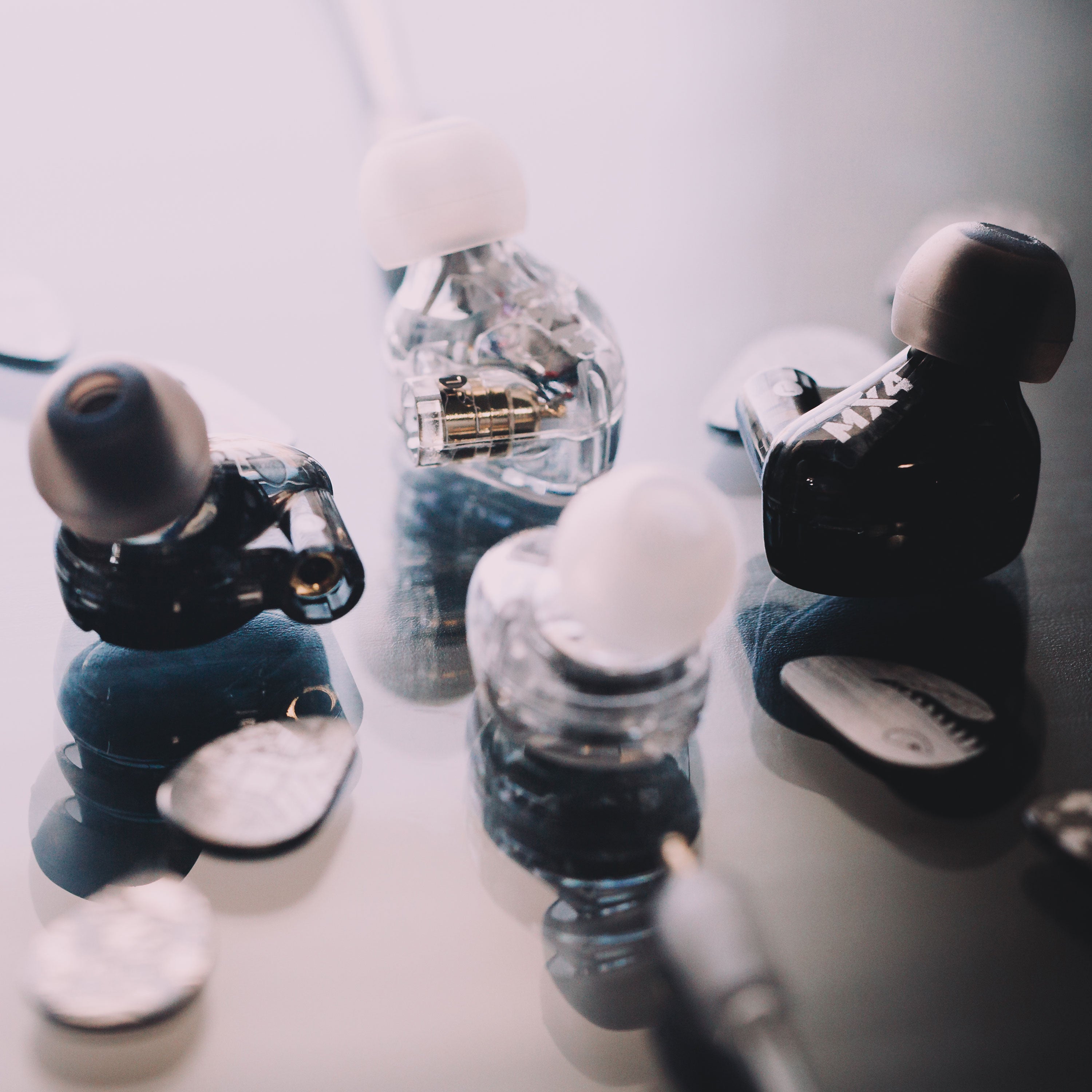 Assorted luxury fountain pen nibs and caps displayed on a reflective surface, showcasing intricate designs and details in black and transparent materials.