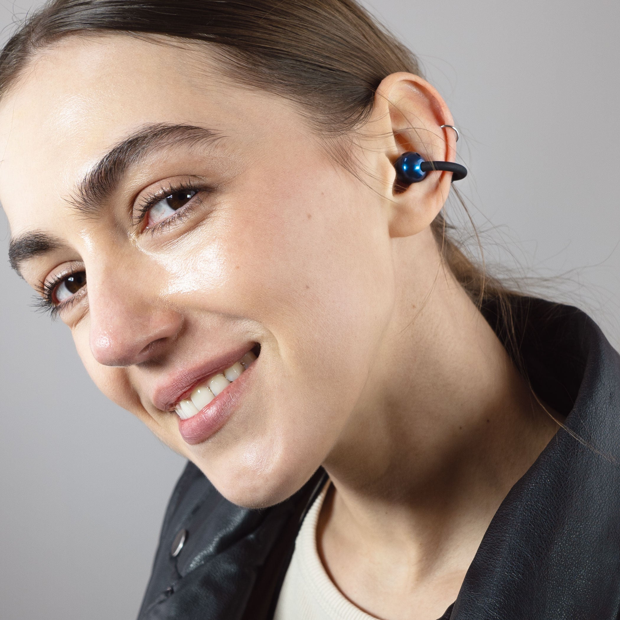 Woman wearing a black Pebbles Air earbud with a gray background