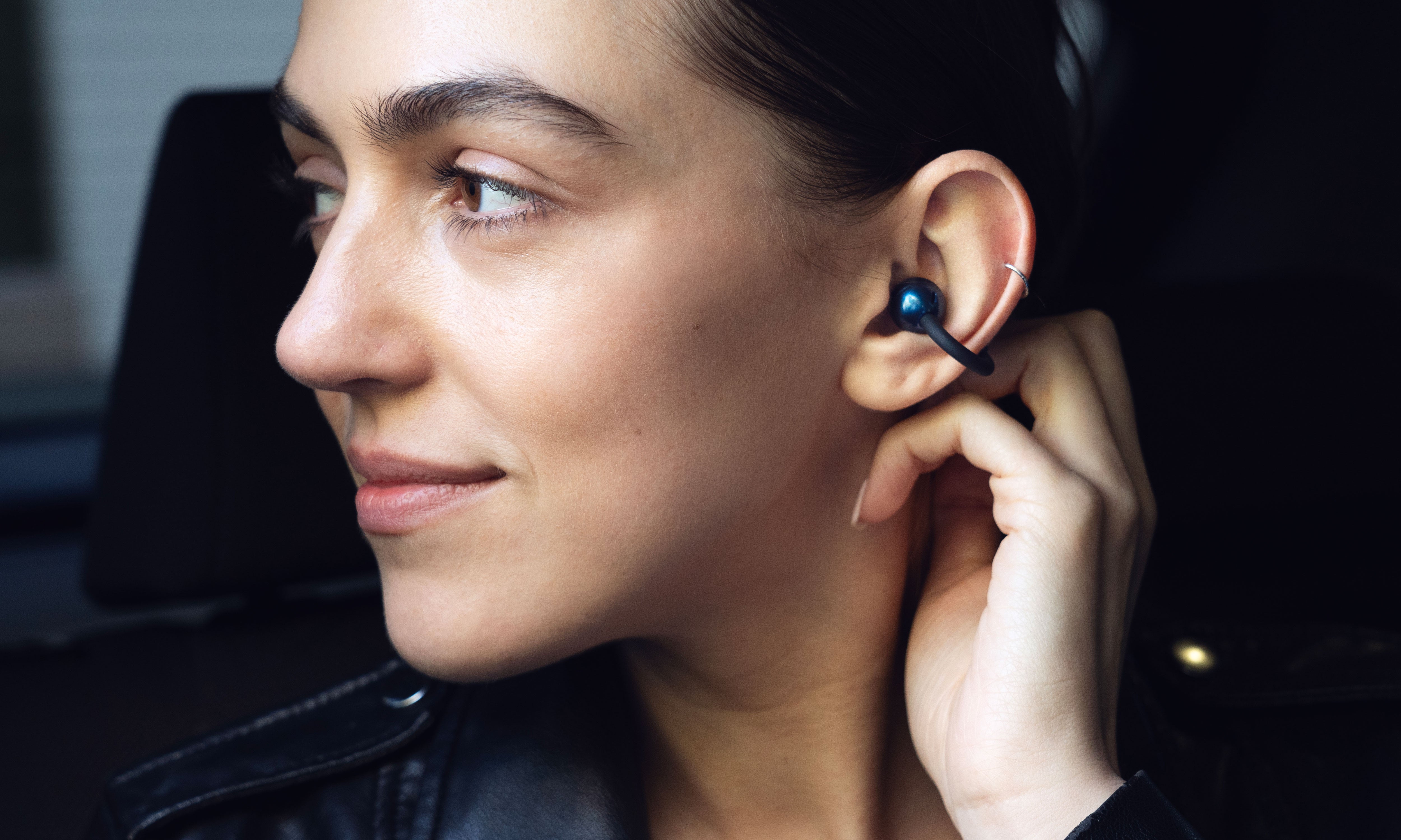 Woman wearing a black Pebbles Air earbud in her ear