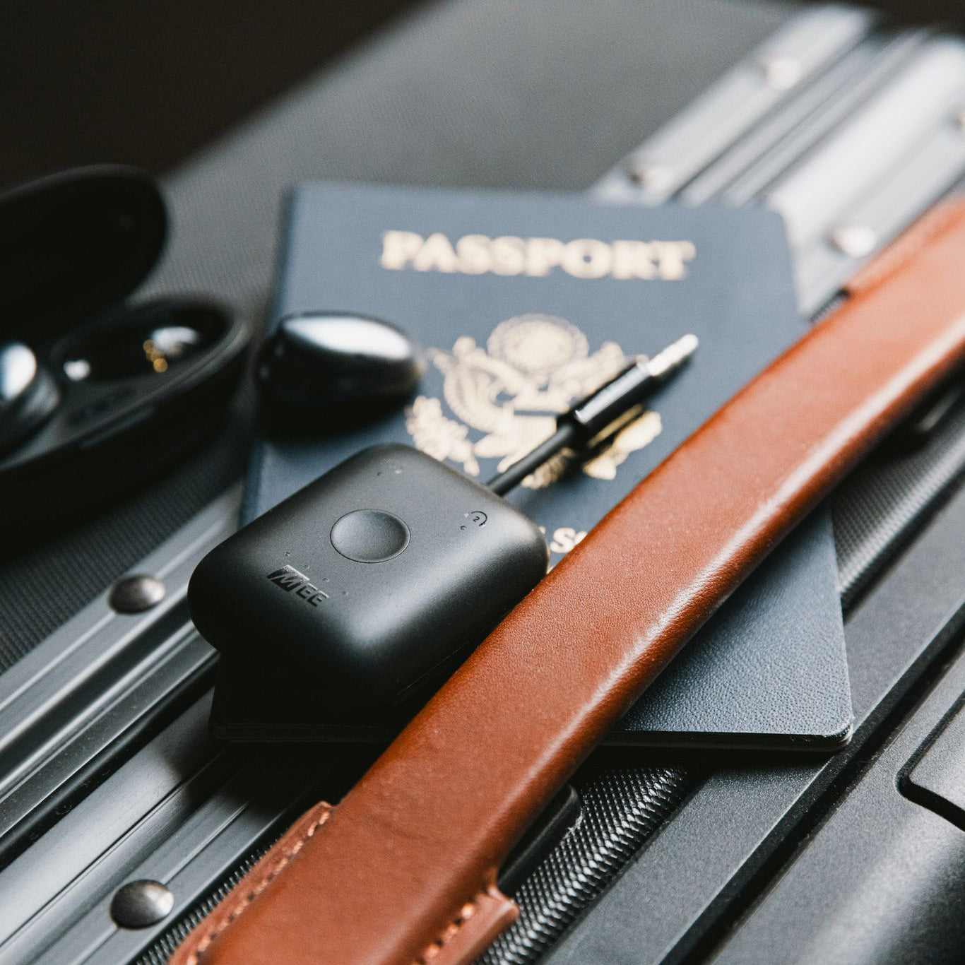 MEE audio Connect Air Bluetooth travel adapters transmitter with the MEE audio Pebbles True Wireless Earbuds and passport on luggage