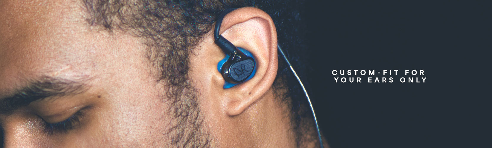 Close-up of a person's left ear wearing a custom-fit blue earbud, with text that reads "custom-fit for your ears only" on a grey background.