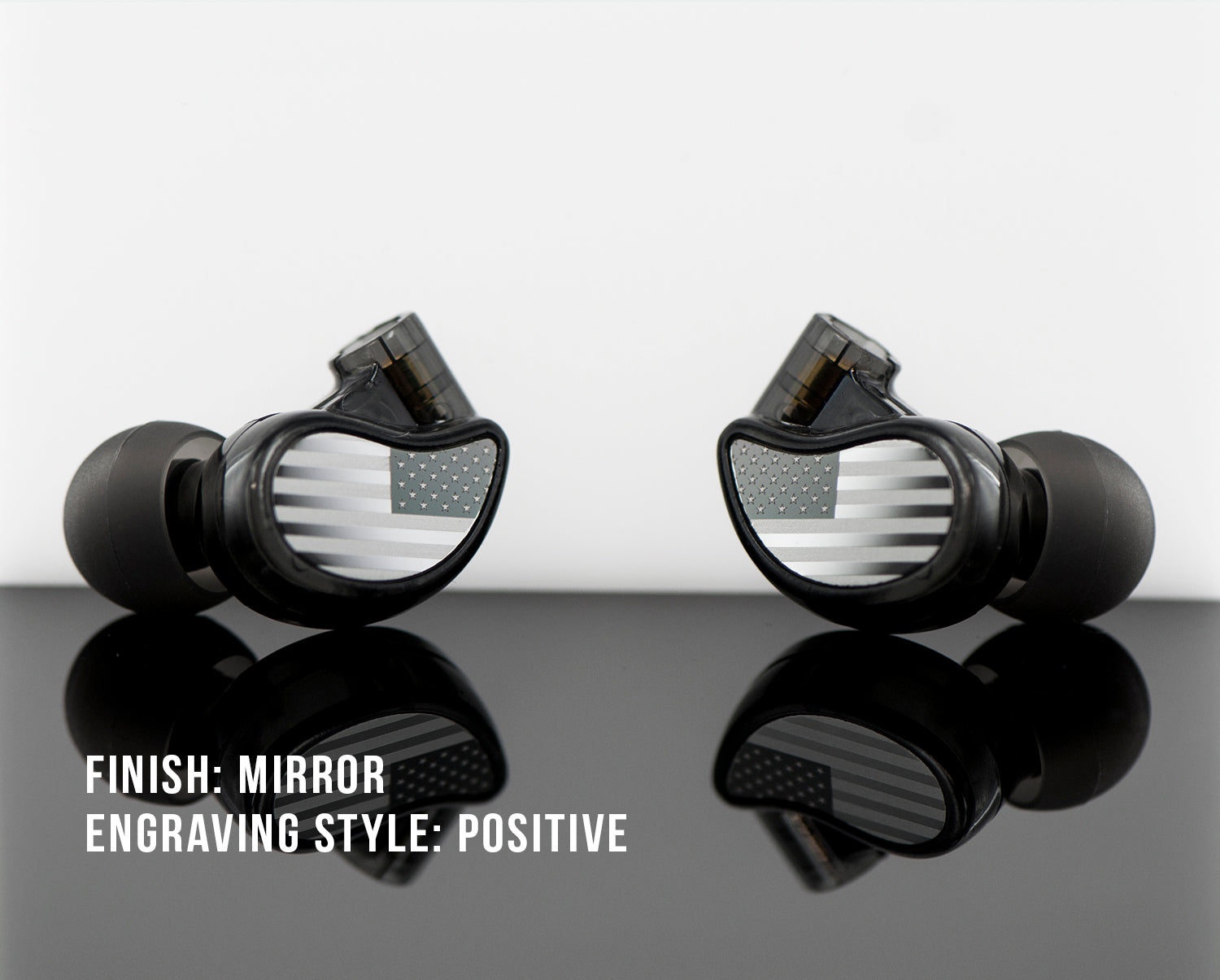 Two black earphones with mirror finish and positive engraving style, featuring a flag design on a reflective surface.