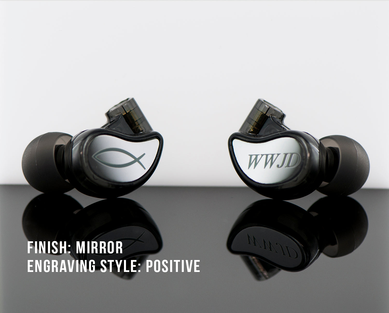 Two customized in-ear monitors with mirror finish, one engraved with an "o" symbol and the other with "wwjd," displayed on a reflective surface with text describing finish and engraving style.
