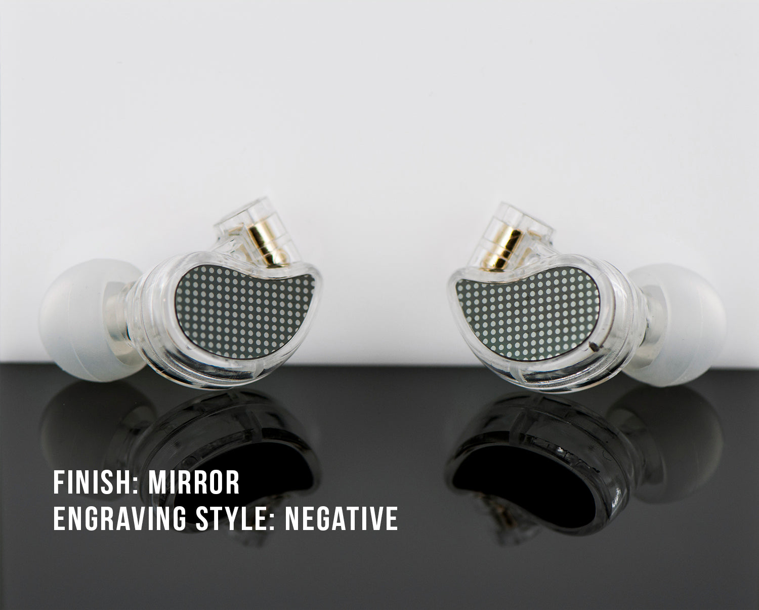 Two high-end in-ear monitors with a mirror finish and negative engraving style, displayed on a reflective surface with labeled text describing their style details.