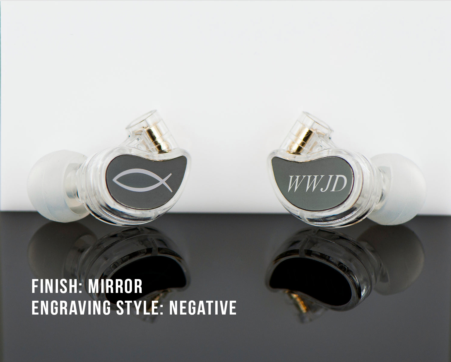 Two custom-engraved, clear in-ear monitors with mirrored finishes reflected on a glossy surface, labeled "finish: mirror, engraving style: negative.