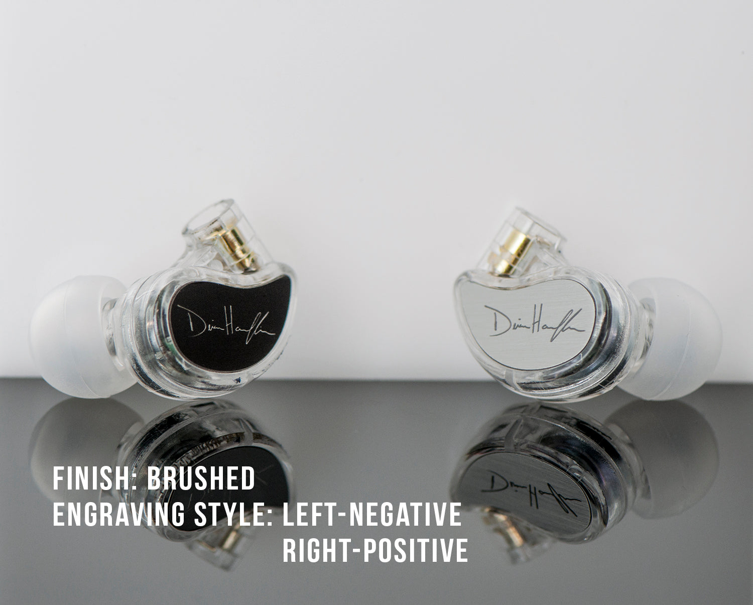 Two customized in-ear monitors on a reflective surface, one with black negative engraving and the other with clear positive engraving, both signed "dihoff".