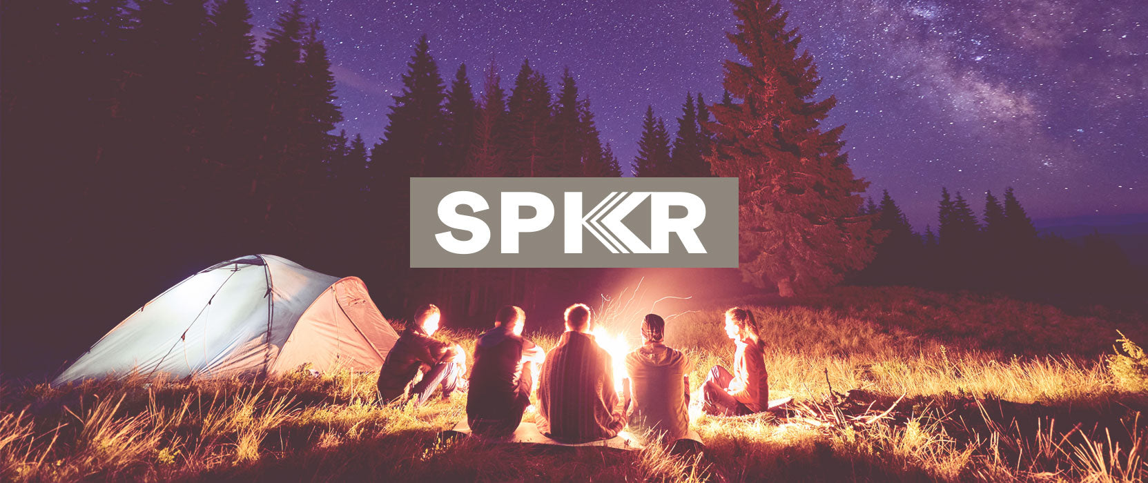 A group of friends sitting around a campfire near a tent under a starry sky in a forest, with the word "spkr" superimposed in the center.
