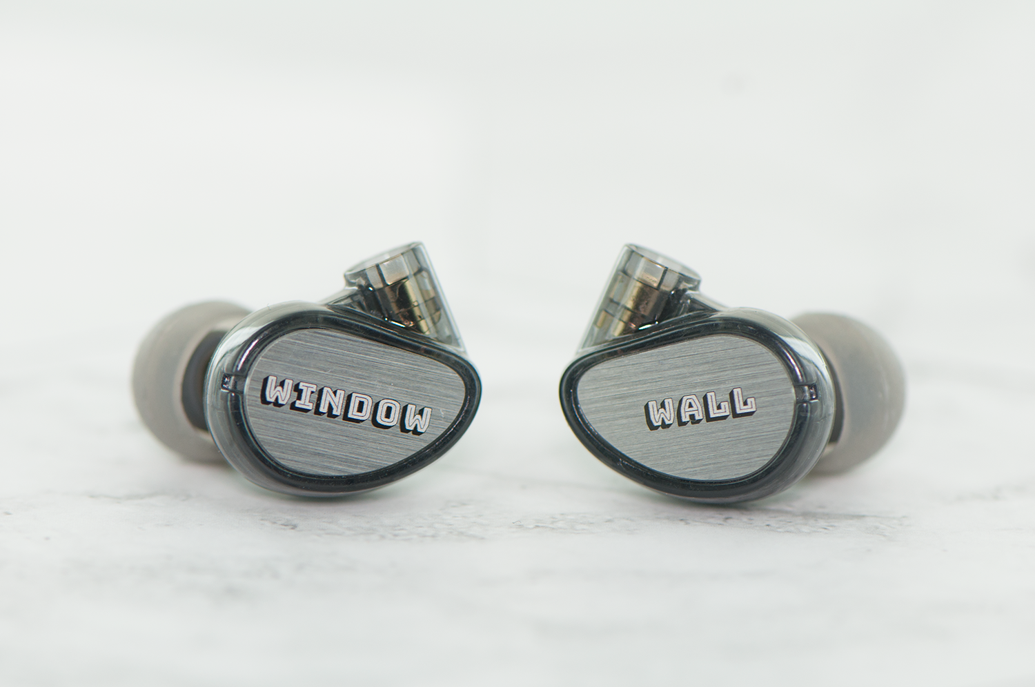 Two earphones with the words "window" and "wall" written on each earpiece, placed against a white background.
