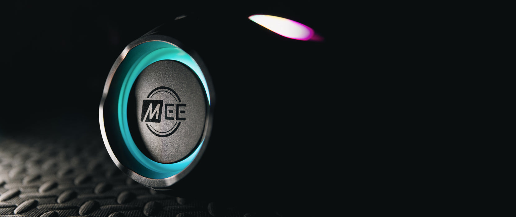 Close-up of a sleek, modern headphone speaker with a glowing blue light and the logo "mee" illuminated, set against a black textured background.
