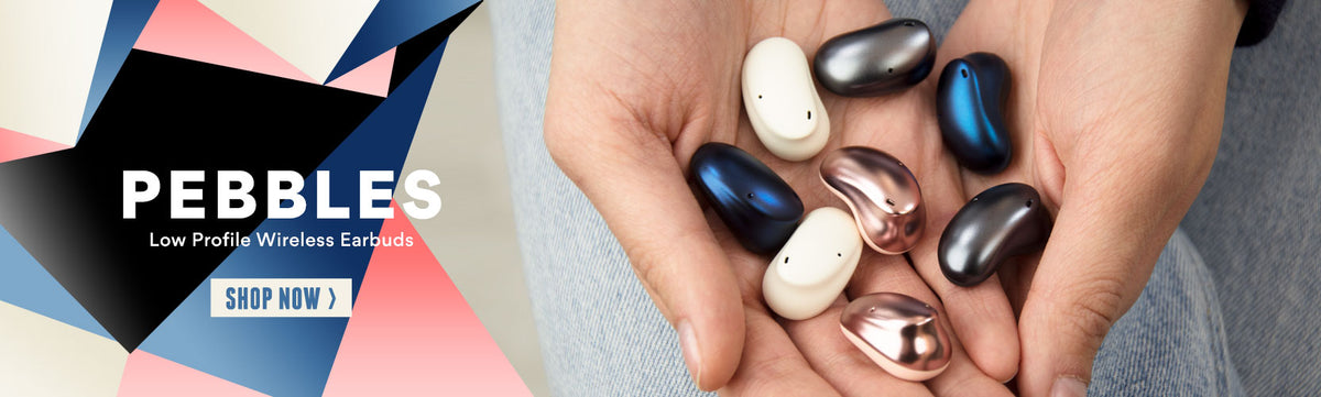 A person holds a selection of smooth, shiny Pebbles earbuds in Onyx, Sandstone, Sapphire and Rose Gold colors, above a promotional banner that reads " Pebbles low profile wireless earbuds - Shop Now"