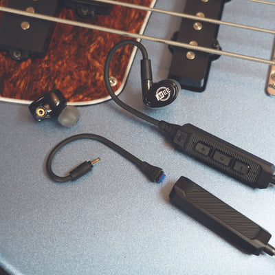 Black MEE audio MX2 PRO Musicians' In-Ear Monitors and a BT3 Hi-Res Bluetooth Audio Adapter displayed on a guitar.