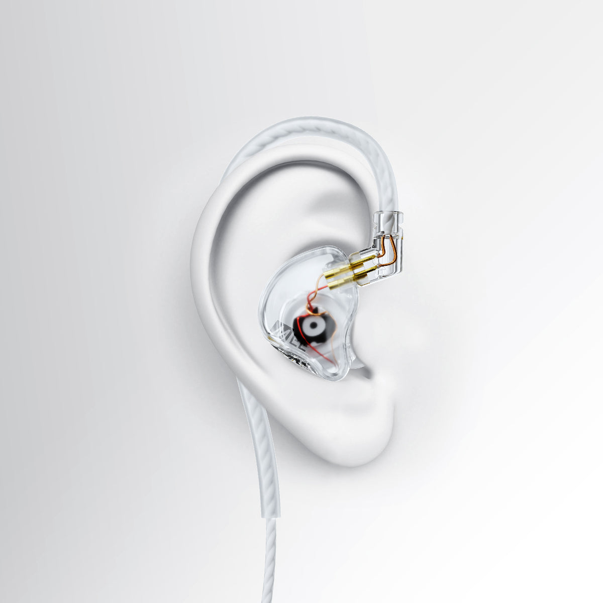A clear MEE audio CORE 3 triple hybrid driver in-ear monitor earphone with a transparent housing and gold-toned internal components, shown mounted on a white ear-shaped form against a light gray background.