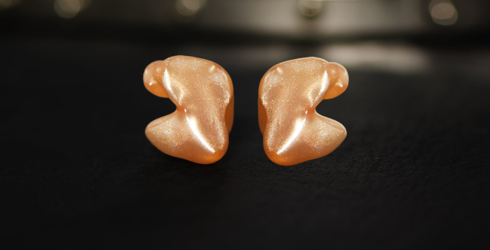 Pair of ISO-Ultra Solid Custom Earplugs for Maximum Hearing Protection on a dark surface