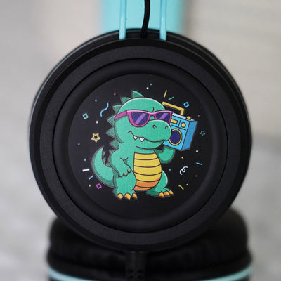 Black KidJamz KJ55AUX headphones faceplate with a cartoon Dinosaur design holding a speaker while in color on a light gray background 