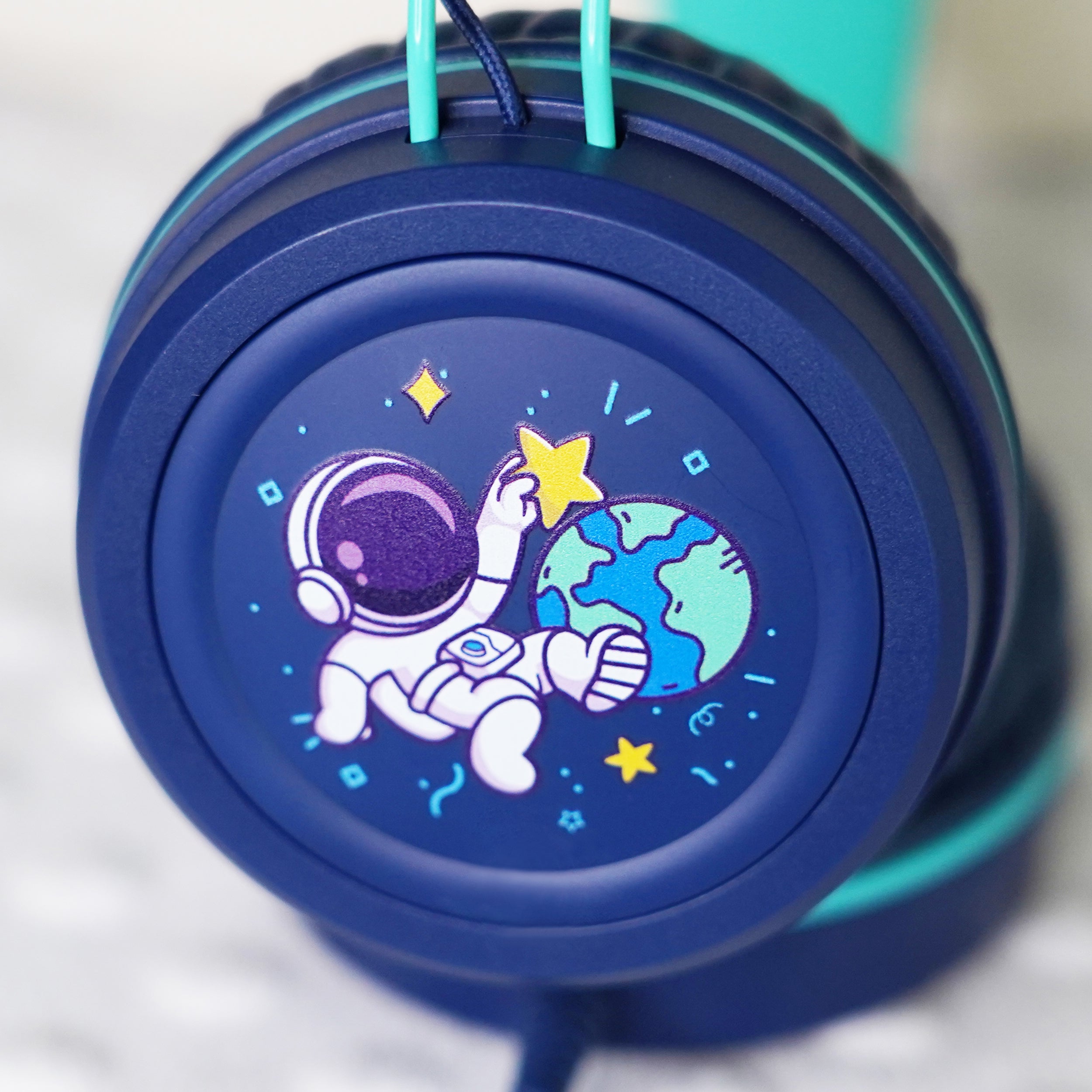 Blue KidJamz KJ55AUX headphones faceplate with a cartoon astronaut design holding a star while in outer space in color on a light gray background 