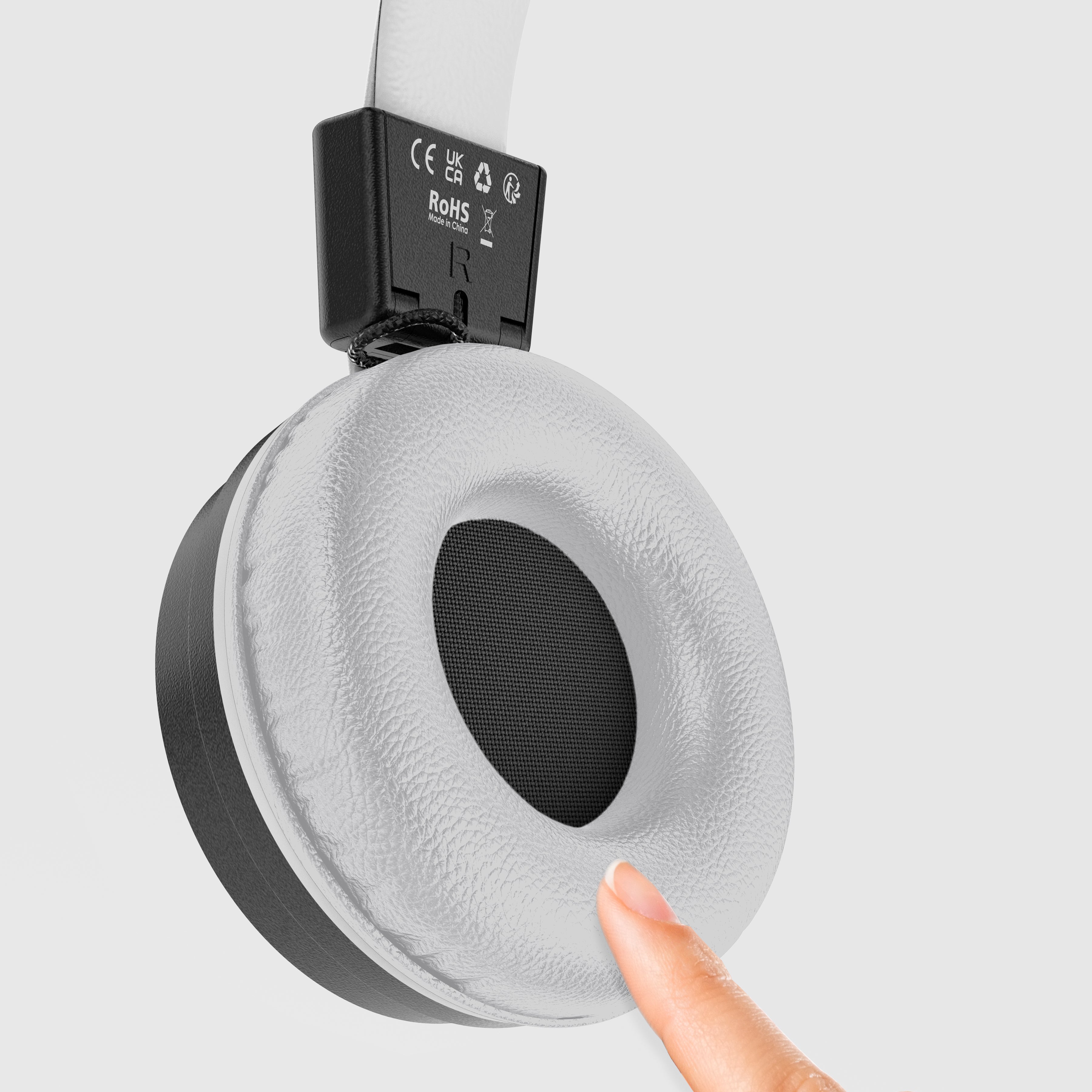 Close-up of a MEE audio KidJamz Share Bluetooth Wireless Headphones for Kids with Multipoint, LED Lights, 85dB Volume Limiter, Microphone, 40h battery; Childrens Headset for School/iPhone/iPad/Tablet with a finger touching the ear cup on a light gray background