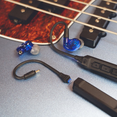 MEE audio M6 PRO Musicians' In-Ear Monitors Wired + Wireless Combo Pack: Includes IEMs, 2 Audio Cables and BT3 Hi-Res Bluetooth Audio Adapter w/aptX, LDAC, Auracast Support, & Built-In Headset (Blue) displayed on a guitar. 