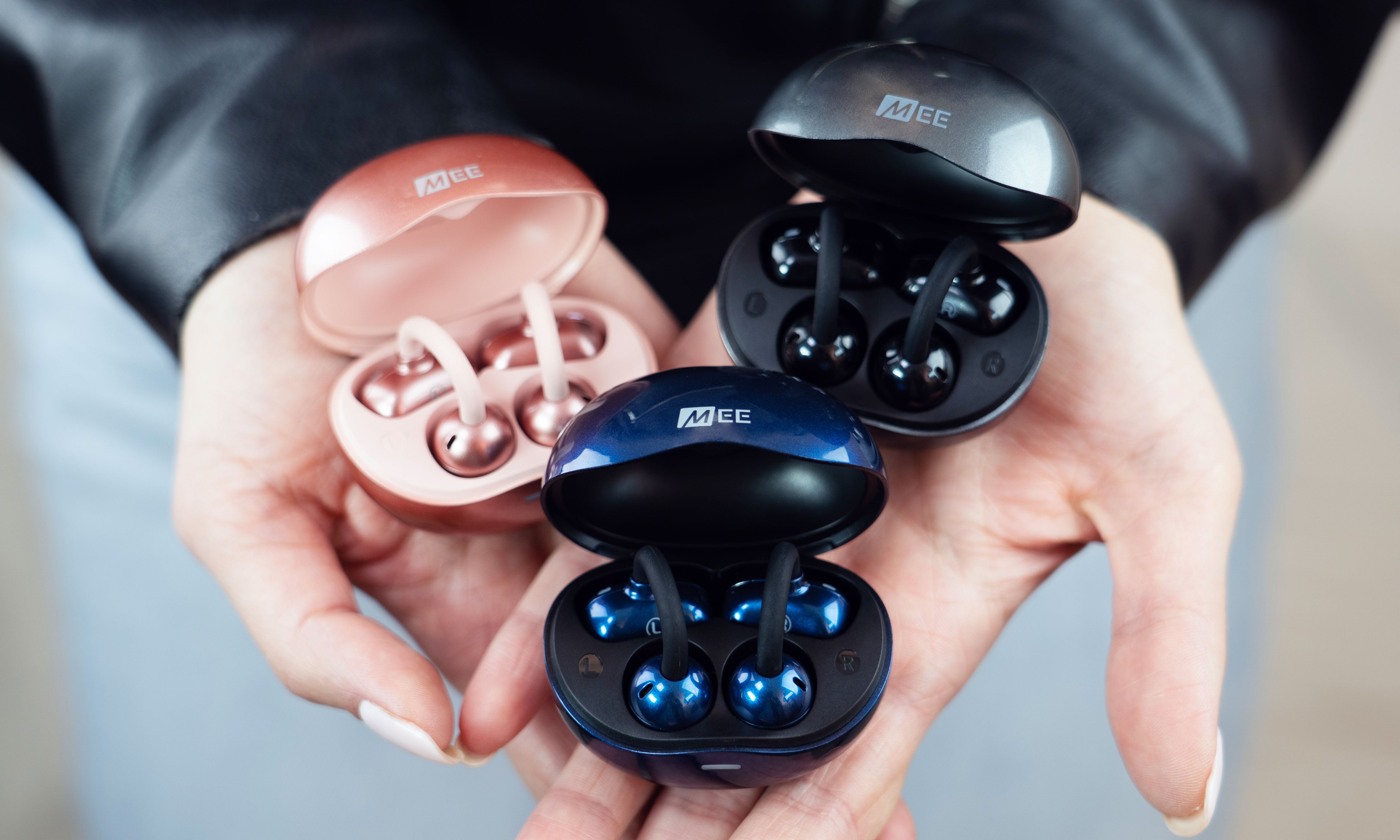 3 Pebbles Air earbuds in their case in different colors held by a person.