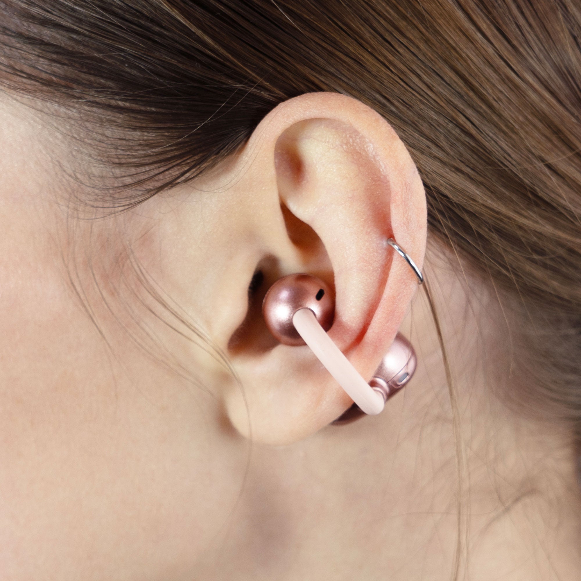 Close-up of a person wearing a pink Pebbles Air earbud.

