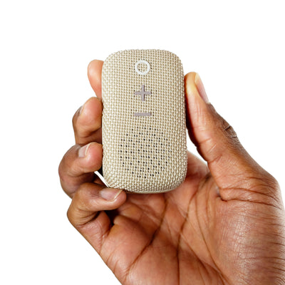 Man holding a Beige MEE audio goSPKR Wearable Clip-on Bluetooth Speaker on a white background